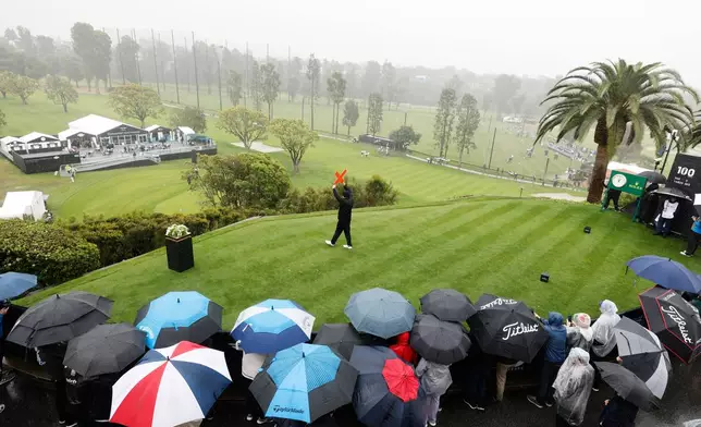 Fans cover themselves with umbrellas as they crowd around a tee during the first round of the Genesis Invitational golf tournament at Riviera Country Club, Thursday, Feb. 19, 2026, in the Pacific Palisades area of Los Angeles. (AP Photo/Caroline Brehman)