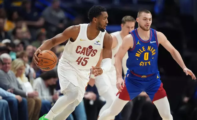 Cleveland Cavaliers guard Donovan Mitchell, left, drives past Denver Nuggets guard Christian Braun (0) in the first half of an NBA basketball game Monday, Feb. 9, 2026, in Denver. (AP Photo/David Zalubowski)