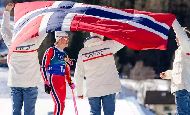 Johannes Hoesflot Klaebo, of Norway, 2nd left, joins his teammates after crossing the finish line to win the gold medal in the cross country skiing men's 4 x 7.5km relay at the 2026 Winter Olympics, in Tesero, Italy, Sunday, Feb. 15, 2026. (AP Photo/Kirsty Wigglesworth)
