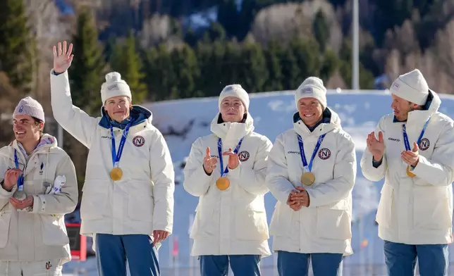Johannes Hoesflot Klaebo, of Norway, waves from the podium, with teammates Einar Hedegart, Martin Loewstroem Nyenget and Emil Iversen, after winning the gold medal in the cross country skiing men's 4 x 7.5km relay at the 2026 Winter Olympics, in Tesero, Italy, Sunday, Feb. 15, 2026. (AP Photo/Kirsty Wigglesworth)