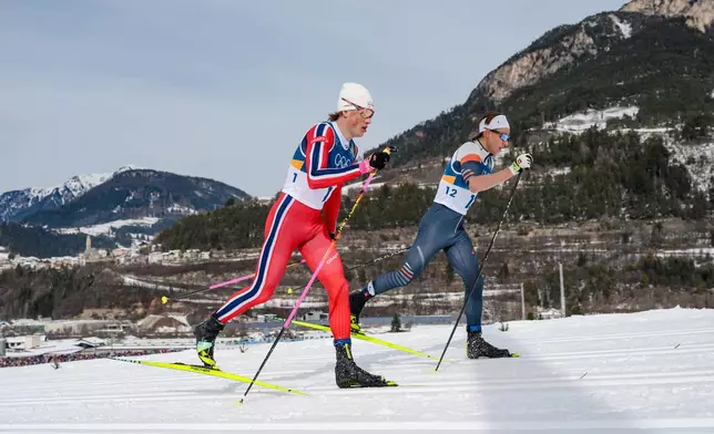 Johannes Hoesflot Klaebo, of Norway, left, and Individual Neutral Athlete Savelii Korostelev compete in the cross country skiing men's 50km mass start Classic at the 2026 Winter Olympics, in Tesero, Italy, Saturday, Feb. 21, 2026. (AP Photo/Evgeniy Maloletka)