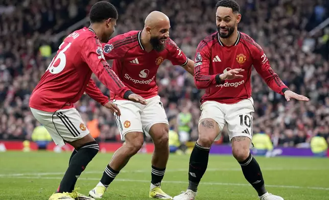 Manchester United's Matheus Cunha, right, celebrates with Manchester United's Amad Diallo, left, and Manchester United's Bryan Mbeumo after scoring his side's second goal during the English Premier League soccer match between Manchester United and Fulham in Manchester, England, Sunday, Feb. 1, 2026. (AP Photo/Dave Thompson)