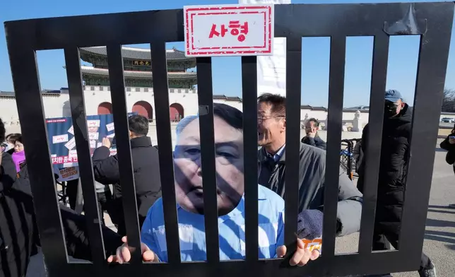 A protester wearing a mask of South Korean former President Yoon Suk Yeol attends a press conference demanding death sentence for Yoon ahead of the court's verdict in Seoul, South Korea, Thursday, Feb. 19, 2026. The sign at top reads, "Death." (AP Photo/Ahn Young-joon)