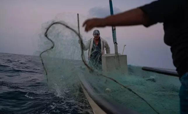 Fisherman Mauricio Contreras casts his nets alongside his daughter at sea near Los Arrecifes, Mexico, Oct. 26, 2025. (AP Photo/Felix Marquez)