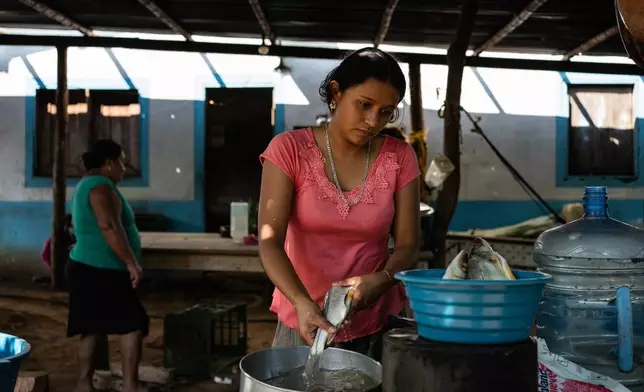 Ana Carolina Hernández cleans fish inside her kitchen to prepare them for cooking in Los Arrecifes, Mexico, Oct. 27, 2025. (AP Photo/Felix Marquez)