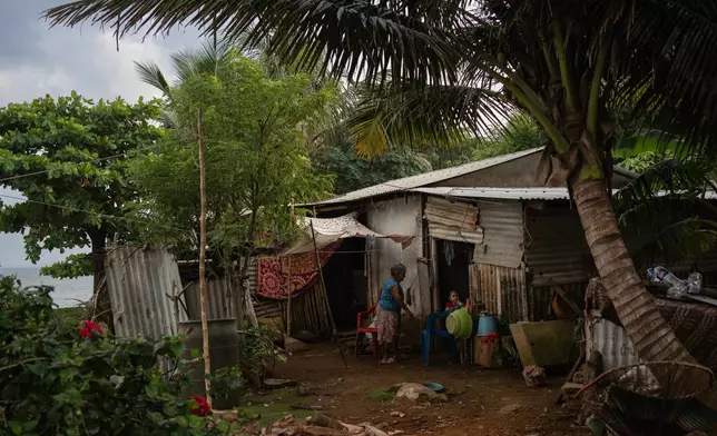 Family members appear at their home near the sea in the community of Zapotitlan, Mexico, Oct. 26, 2025. (AP Photo/Felix Marquez)