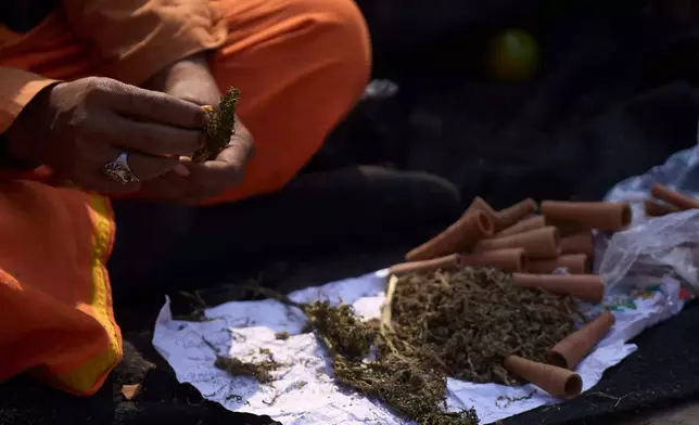 A man displays marijuana and smoking pots to sell to devotees during Maha Shivaratri festival at the Pashupatinath temple premises in Kathmandu, Nepal, Sunday, Feb. 15, 2026. (AP Photo/Niranjan Shrestha)