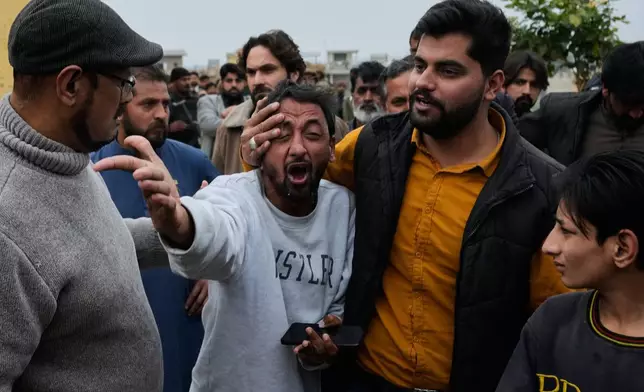 People comfort a man, center, mourning over the death of his relative, close to the site of a bomb explosion at a Shiite mosque, in Islamabad, Pakistan, Friday, Feb. 6, 2026. (AP Photo/Anjum Naveed)