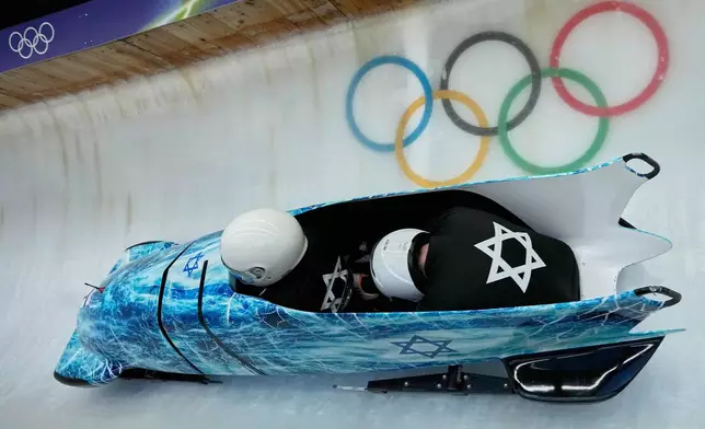 Israel's Adam Edelman, left, slides down the track during a two man bobsled training session at the 2026 Winter Olympics, in Cortina d'Ampezzo, Italy, Friday, Feb. 13, 2026. (AP Photo/Aijaz Rahi)