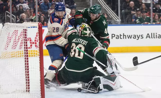 Minnesota Wild goalie Jesper Wallstedt (30) makes the save as Edmonton Oilers' Jack Roslovic (28) and Wild's Daemon Hunt (48) battle for the rebound during second period NHL action, in Edmonton on Saturday, Jan. 31, 2026. (Jason Franson/The Canadian Press via AP)
