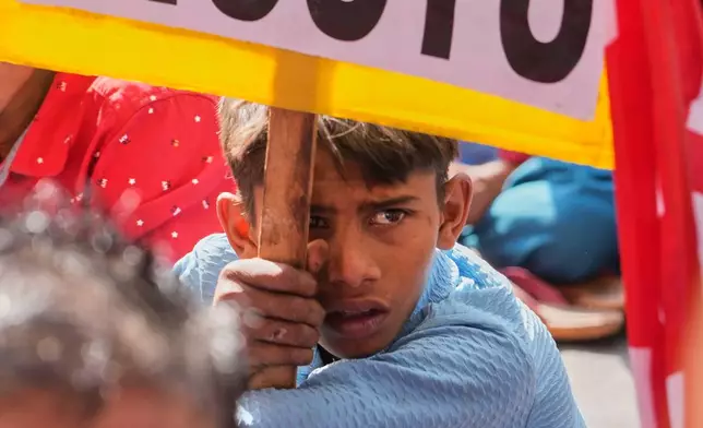 A boy holds a banner during trade unions nationwide strike to protest an interim trade deal with the United States, saying the agreement undermines the interests of farmers, small businesses and workers in New Delhi, India, Thursday, Feb. 12, 2026. (AP Photo/Manish Swarup)