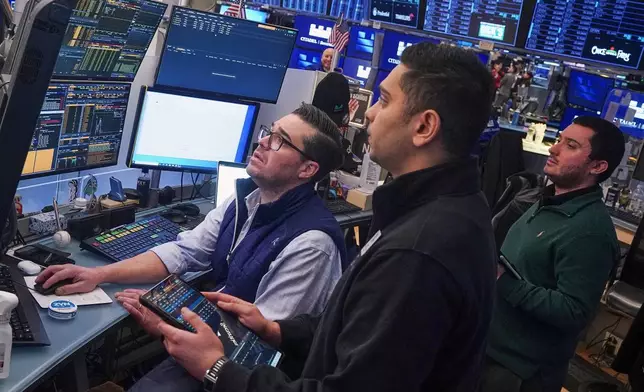 Traders Joseph Lawler, left, and Niall Pawa, center, and Drew Cohen work on the floor of the New York Stock Exchange, Thursday, Feb. 19, 2026. (AP Photo/Richard Drew)