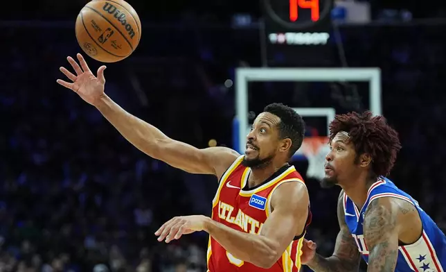 Atlanta Hawks' CJ McCollum, left, reaches for a loose ball next to Philadelphia 76ers' Kelly Oubre Jr. during the first half of an NBA basketball game Thursday, Feb. 19, 2026, in Philadelphia. (AP Photo/Matt Rourke)