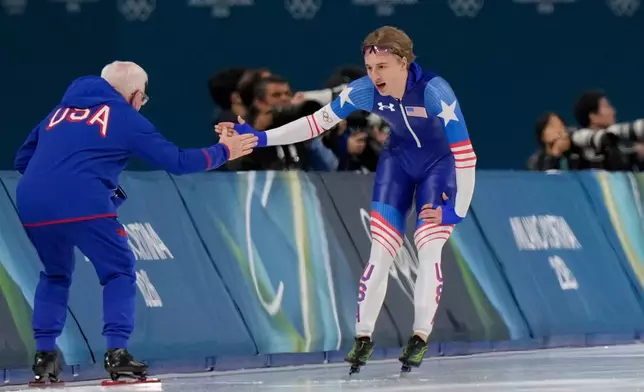 Jordan Stolz of the U.S. celebrates with his catch Bob Corby, left, after the men's 1,000 meters speedskating race at the 2026 Winter Olympics, in Milan, Italy, Wednesday, Feb. 11, 2026. (AP Photo/Luca Bruno)