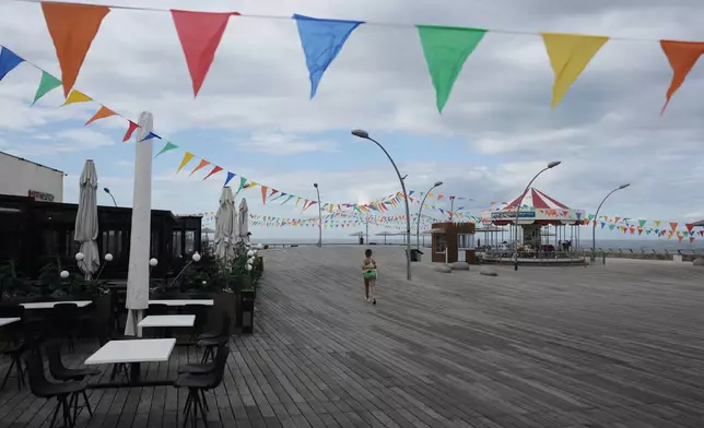 A woman runs on empty boardwalk at the Tel Aviv , Israel, port after alarms announced that Israel had launched an attack on Iran, Saturday, Feb. 28, 2026. (AP Photo/Oded Balilty)