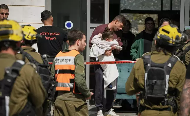 Residents evacuate a building hit by a projectile in Tirat Hacarmel, northern Israel, Saturday, Feb. 28, 2026. No injuries were reported. (AP Photo/Leo Correa)