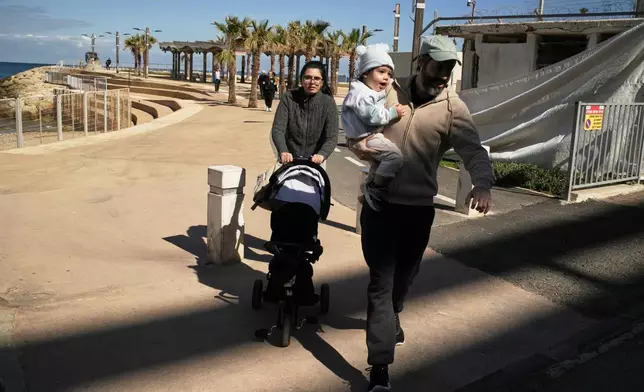 A couple with their two children rush to a shelter after a warning siren sounds following Israeli strikes in Iran, in Haifa, northern Israel, Saturday, Feb. 28, 2026. (AP Photo/Leo Correa)