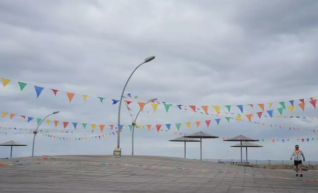 A man walks on empty boardwalk at the Tel Aviv port , Israel, after alarms announced that Israel had launched an attack on Iran, Saturday, Feb. 28, 2026. (AP Photo/Oded Balilty)