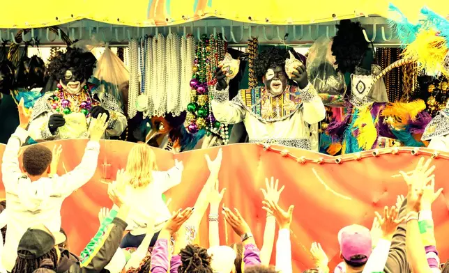 A member of the Krewe of Zulu offers up coconuts on Mardi Gras Day, Tuesday, Feb. 17, 2026 in New Orleans. (AP Photo/Matthew Hinton)