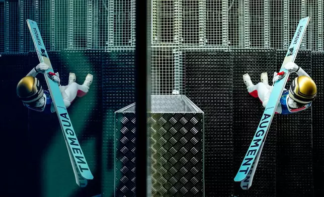 Lisa Eder, of Austria, is reflected on a window while getting ready to jump during a ski jumping, women's normal hill, training session, at the 2026 Winter Olympics, in Predazzo, Italy, Thursday, Feb. 5, 2026. (AP Photo/Matthias Schrader)