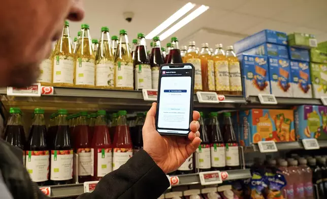 Ian Rosenfeldt, the creator of "Made O'Meter" mobile app, demonstrates how shoppers can use the application to identify and boycott American goods in a grocery store in Copenhagen, Wednesday, Jan. 28, 2026. (AP Photo/James Brooks)