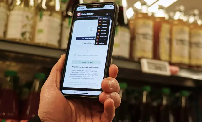 Ian Rosenfeldt, the creator of "Made O'Meter" mobile app, demonstrates how shoppers can use the application in different languages to identify and boycott American goods in a grocery store in Copenhagen, Wednesday, Jan. 28, 2026. (AP Photo/James Brooks)