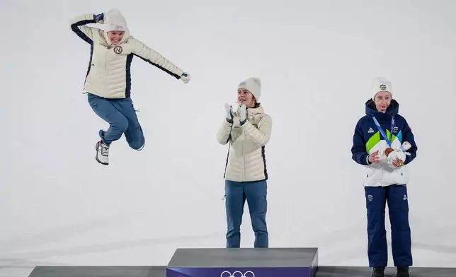 Gold medalist Anna Odine Stroem, of Norway, applauds as silver medalist Eirin Maria Kvandal, also of Norway, celebrates and bronze medalist Nika Prevc, of Slovenia, right, applauds after the ski jumping women's large hill individual at the 2026 Winter Olympics, in Predazzo, Italy, Sunday, Feb. 15, 2026. (AP Photo/Matthias Schrader)