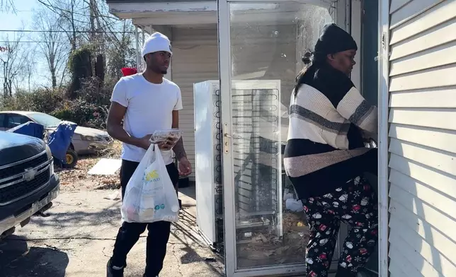 Chiquitta Fields and her son bring their belongings inside their home on Monday, Feb. 2, 2026, in Belzoni, Miss.. (AP Photo/Sophie Bates)