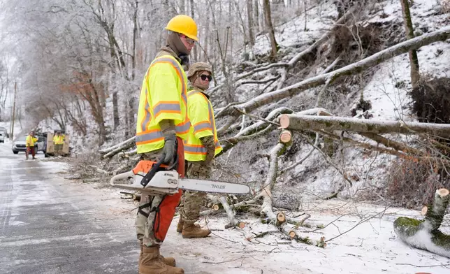 Tennessee National Guard Specialist Taylor Osteen, left, holds a chainsaw as he takes a break from cutting trees from a road Friday, Jan. 30, 2026, in Nashville, Tenn. (AP Photo/George Walker IV)
