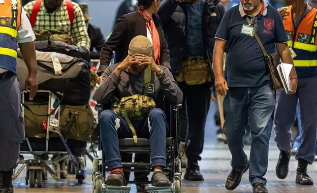 South African men who were allegedly tricked into fighting for Russia in the war in Ukraine are escorted by police officers as they arrive at King Shaka International Airport in Durban, South Africa, Wednesday, Feb. 25, 2026. (AP Photo/Str)