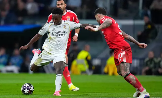 Real Madrid's Vinicius Junior, left, and Benfica's Nicolas Otamendi, right, challenge for the ball during the second leg of the Champions League playoff soccer match between Real Madrid and Benfica in Madrid, Spain, Wednesday, Feb. 25, 2026. (AP Photo/Manu Fernandez)