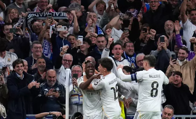 Real Madrid's Vinicius Junior, left, celebrates with teammates after scoring his side's second goal during the second leg of the Champions League playoff soccer match between Real Madrid and Benfica in Madrid, Spain, Wednesday, Feb. 25, 2026. (AP Photo/Manu Fernandez)