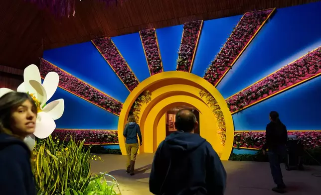 Staff members walk through a doorway with sunbeams made of orchids as finishing touches are placed on the 12th annual Chicago Botanic Garden Orchid Show, Friday, Feb. 6, 2026, in Glencoe, Ill. (AP Photo/Erin Hooley)