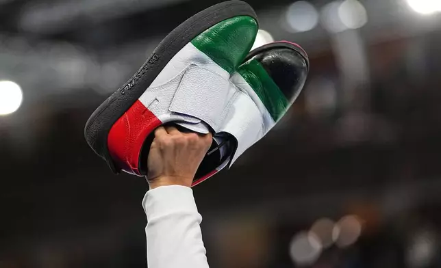 Italy's Mattia Giovanella gestures holding his shoes, after the men's curling round robin session against Britain, at the 2026 Winter Olympics, in Cortina d'Ampezzo, Italy, Friday, Feb. 13, 2026. (AP Photo/Fatima Shbair)