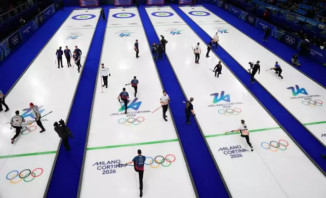 Athletes warm up before a men's curling round robin session at the 2026 Winter Olympics, in Cortina d'Ampezzo, Italy, Monday, Feb. 16, 2026. (AP Photo/David J. Phillip)