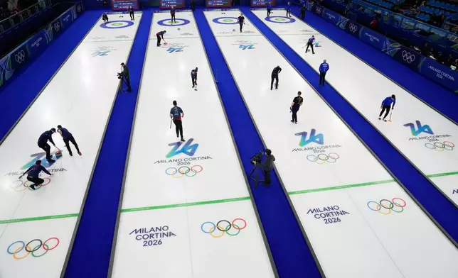 Athletes warm up before the start of a men's curling round robin session at the 2026 Winter Olympics, in Cortina d'Ampezzo, Italy, Monday, Feb. 16, 2026. (AP Photo/David J. Phillip)