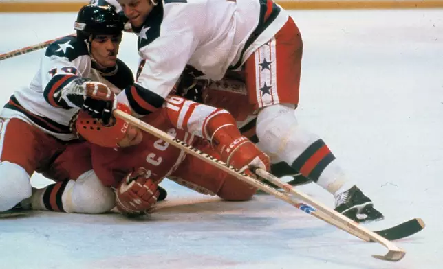 United States' hockey players Mark Johnson, left and Bill Baker, right, battle Soviet Union's Vladimir Petrov (16) for the puck during a medal round match at the 1980 Winter Olympics in Lake Placid, N.Y., Feb. 22, 1980. (AP Photo/File)
