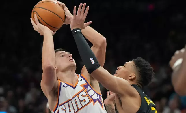 Phoenix Suns guard Collin Gillespie (12) shoots over Golden State Warriors guard Brandin Podziemski during the first half of an NBA basketball game, Thursday, Feb. 5, 2026, in Phoenix. (AP Photo/Rick Scuteri)
