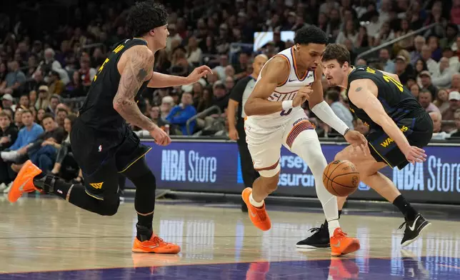 Phoenix Suns forward Ryan Dunn drives past Golden State Warriors forward Gui Santos and center Quinten Post during the first half of an NBA basketball game, Thursday, Feb. 5, 2026, in Phoenix. (AP Photo/Rick Scuteri)