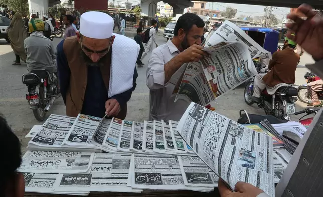 People read morning newspapers covering headline story about overnight cross border fighting between Pakistan and Afghan forces, at a stall in Peshawar, Pakistan, Friday, Feb. 27, 2026. (AP Photo/Muhammad Sajjad)