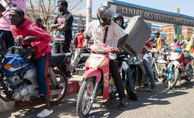 A student transports his belongings on a motorcycle taxi as he leaves the Cheikh Anta Diop University, which is being evacuated following the death of second year student Abdoulaye Ba, in Dakar Tuesday, Feb. 10, 2026. (AP Photo/Sylvain Cherkaoui)