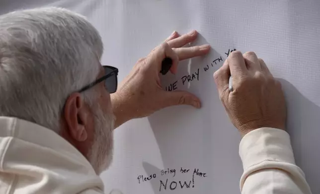 Jeff Robb, a Seattle resident wintering in Tucson, signs a banner supporting Nancy Guthrie in Tucson Ariz., on Friday, Feb. 13, 2026. (AP Photo/Ty ONeil)