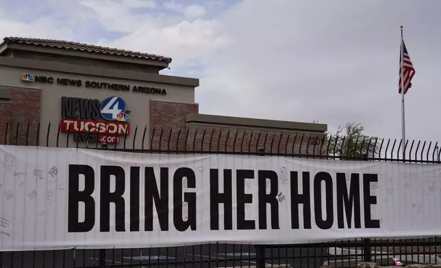 A banner reading "Bring her home" on a fence outside of the KVOA news station in Tucson, Ariz., on Friday, Feb. 13, 2026. (AP Photo/Ty ONeil)
