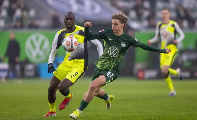 Dortmund's Serhou Guirassy, left, and Wolfsburg's Jan Buerger fight for the ball during their German Bundesliga soccer match in Wolfsburg, Germany, Saturday, Feb. 7, 2026. (David Inderlied/dpa via AP)