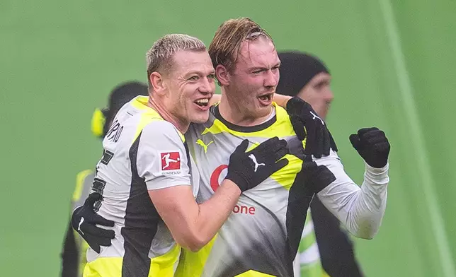 Dortmund's Julian Ryerson, left, and Julian Brand celebrate after their team's first goal during their German Bundesliga soccer match against Wolfsburg in Wolfsburg, Germany, Saturday, Feb. 7, 2026. (David Inderlied/dpa via AP)