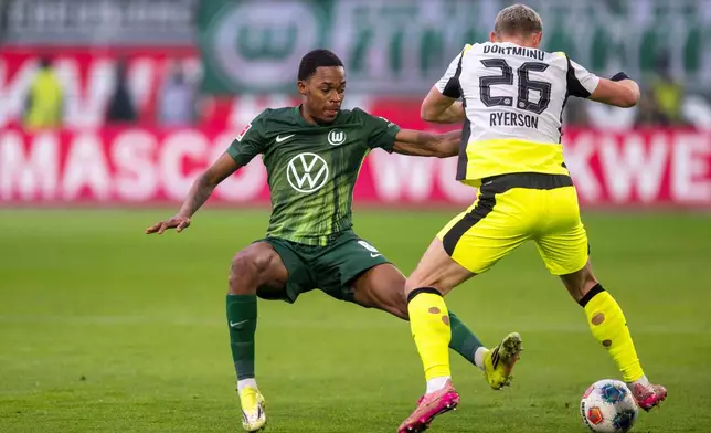 Dortmund's Julian Ryerson, right, and Wolfsburg's Jeanuel Belocian fight for the ball during their German Bundesliga soccer match in Wolfsburg, Germany, Saturday, Feb. 7, 2026. (David Inderlied/dpa via AP)