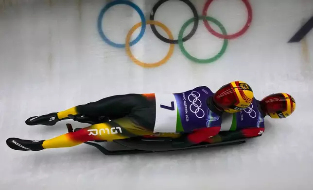 Germany's Toni Eggert, left, and Florian Mueller, right, slide down the track during a men's doubles luge run at the 2026 Winter Olympics, in Cortina d'Ampezzo, Italy, Wednesday, Feb. 11, 2026. (AP Photo/Aijaz Rahi)