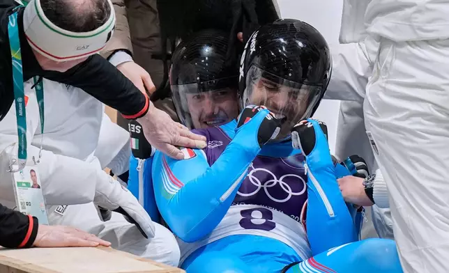 Italy's gold medalists Emanuel Rieder, right, and Simon Kainzwaldner, left, celebrate as they arrive at the finish during a men's doubles luge run at the 2026 Winter Olympics, in Cortina d'Ampezzo, Italy, Wednesday, Feb. 11, 2026. (AP Photo/Aijaz Rahi)