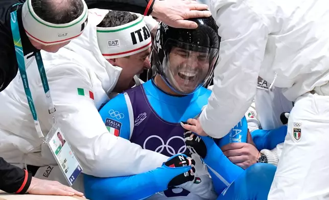 Italy's Emanuel Rieder and Simon Kainzwaldner celebrate as they arrive at the finish during a men's doubles luge run at the 2026 Winter Olympics, in Cortina d'Ampezzo, Italy, Wednesday, Feb. 11, 2026. (AP Photo/Aijaz Rahi)