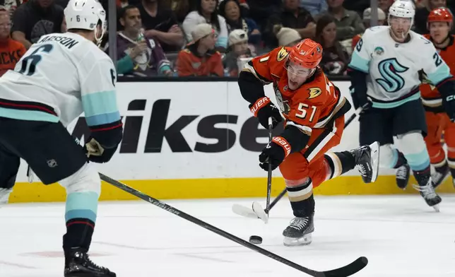 Anaheim Ducks defenseman Olen Zellweger (51) shoots as Seattle Kraken defenseman Adam Larsson (6) defends during the first period of an NHL hockey game, Tuesday, Feb. 3, 2026, in Anaheim, Calif. (AP Photo/Kyusung Gong)